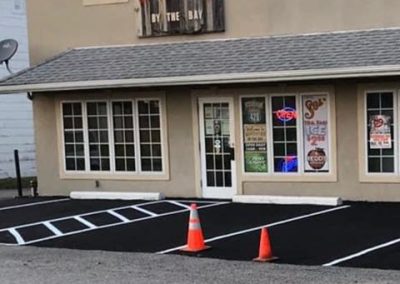 Two-story building with a sign above the door, "Martellucci's Pizzeria." Orange cones in parking lot.