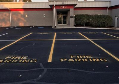 A building with a BVFC sign and multiple "Fire Parking" spots painted in yellow on the parking lot.