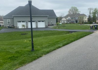 Suburban street with green lawns, a lamppost, large houses, and overcast sky.