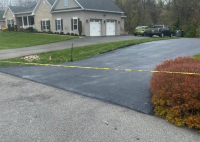 House with a garage, driveway marked with yellow tape, and overcast sky.