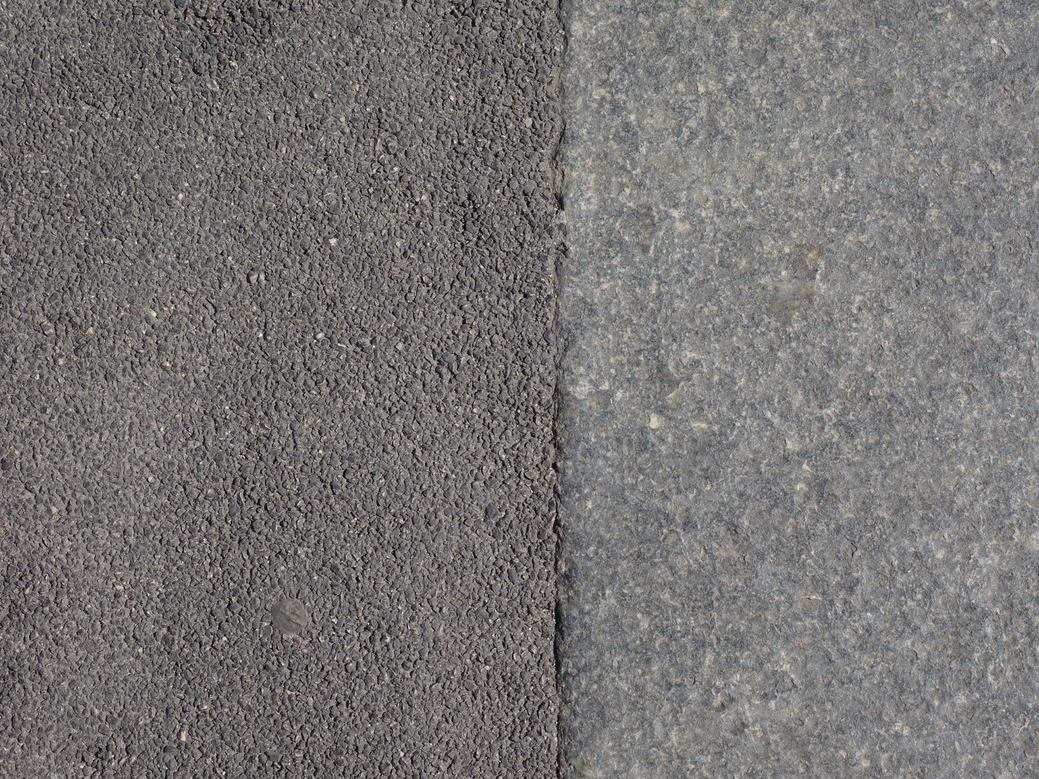 Close-up of textured asphalt on the left and smooth gray concrete on the right, divided by a straight line.